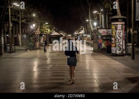 Barcelona, Spanien. Oktober 2020. 25. Oktober 2020, Barcelona, Katalonien, Spanien: Eine Frau spaziert in der ersten Nacht der Ausgangssperre durch den einsamen Boulevard Las Ramblas in Barcelona. Der spanische Premierminister hat heute einen neuen Ausnahmezustand genehmigt, der bis Mai in Kraft bleiben soll, und die katalanische Regierung verhängt zwischen 22 und 6 Uhr eine obligatorische Ausgangssperre. Quelle: Jordi Boixareu/Alamy Live News Stockfoto