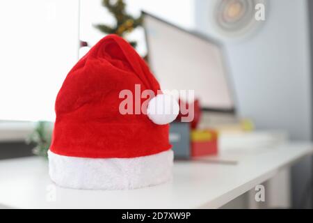 Auf dem Desktop ist ein roter weihnachtsmann Hut mit Geschenkboxen und Computer. Stockfoto