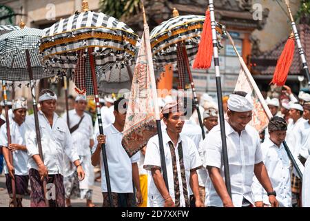 Galungan Urlaub. Festliche Prozession von jungen Jungs mit Regenschirmen in den Händen. Bali, Indonesien. Nahaufnahme. 26.12.2018. Stockfoto