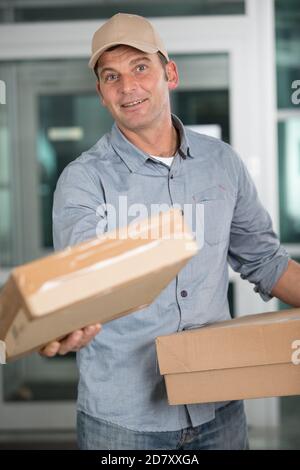 Deliveryman in Uniform hält Pakete Stockfoto