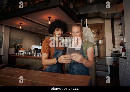 Junge ernsthafte Mitarbeiter mit digitalen Tablet, während im modernen Stand Café Stockfoto