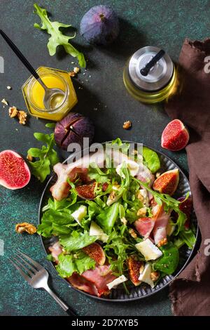 Gesunde Ernährung Konzept. Herbstsalat mit Feigen, Prosciutto, Rucola, Spinat, Käse, Walnüssen und Honig auf einer Steinplatte. Draufsicht flach liegend Rückenlage Stockfoto