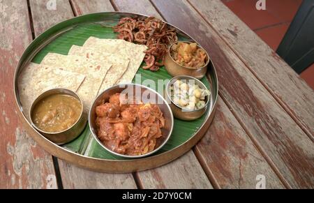 Mahlzeiten auf Bananenblatt in einem runden Metallplatte serviert, eine berühmte südindische Küche. Stockfoto