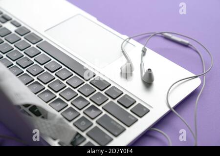 Ohrhörer auf dem Computer Laptop. Violette Tischplatte. Stockfoto
