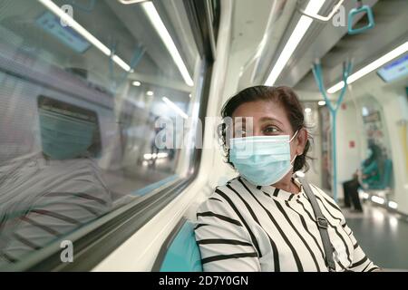 Frau Pendler trägt Gesichtsmaske in U-Bahn-Zug. Während einer Pandemie normal reisen. Stockfoto