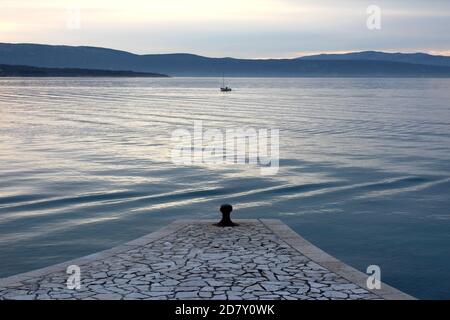 Panoramablick auf traditionelle Steinfliesen, überdachter Pier und einone Fischer Angeln auf kleinen Fischerboot in der Mitte der lokalen bucht Stockfoto