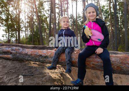 Portrait von zwei niedlichen liebenswert fröhlich verspielt kaukasischen Geschwister Kinder, Junge und Mädchen, Spaß zu Fuß Frühling oder Herbst Wald und essen Snack Stockfoto