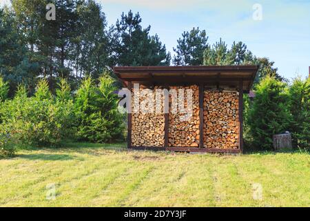 Brennholz für die Heizung im Winter geerntet. Ein Haufen Brennholz im Hof des Hauses auf dem grünen Gras Stockfoto