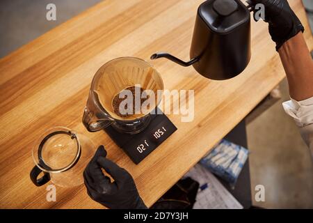 Heißer Kaffee, der durch den Papierfilter auf den Holztisch fließt Stockfoto