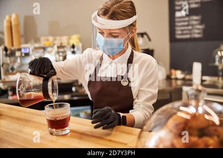 Blonde charmante Frau in schützende Medizin Maske arbeiten an der Kaffeebar Stockfoto