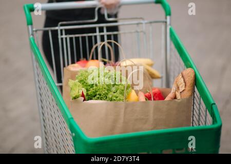 Lebensmittel aus einem Supermarkt in einem Trolley im Freien. Lieferung von Lebensmitteln während der Quarantäne. Cruft Paper Öko Taschen zum Einkaufen. Frisches Obst und Gemüse Stockfoto