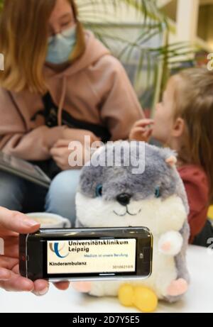 23. Oktober 2020, Sachsen-Anhalt, Köthen: In der Kinderklinik des Universitätsklinikums hält eine Mutter mit ihren beiden Kindern an einem Tisch in der Cafeteria einen Pager (Pager-Empfänger) in der Hand. Mit einem summenden Geräusch signalisiert der Pager den Anruf zum Sprechzimmer. In der aktuellen Zeit mit steigenden Koronazahlen soll das neue Paging-System, das Patienten bis zu 500 Meter entfernt bewegen kann, die Situation in den Wartebereichen ausgleichen. Die Pager sollten es ermöglichen, die Entfernungen auch bei einer großen Menschenmenge zu halten. Die Funkruf-Empfänger befinden sich derzeit Stockfoto