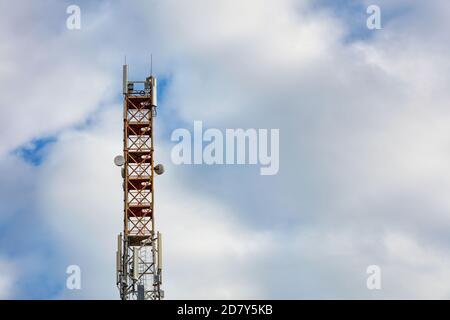 Telekommunikationsturm der 3G-, 4G- und 5G-Mobilfunkkommunikation mit Antennen gegen einen blauen bewölkten Himmel. Stockfoto