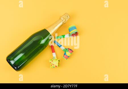 Flasche Champagner mit Whistle Party auf gelbem Hintergrund dekoriert. Speicherplatz kopieren. Stockfoto