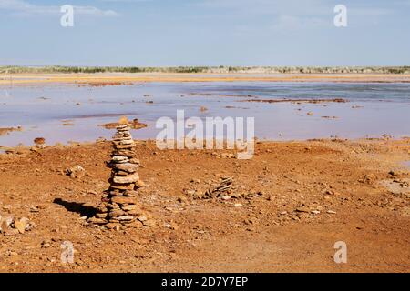 Schlammiger Boden mit Quellwasser, mit Steinhaufen auf einer Seite. Foto in Qinghai, China. Stockfoto