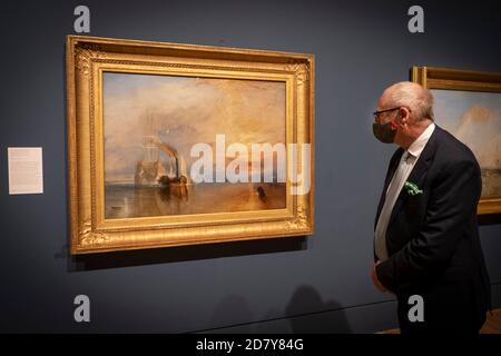 London, England. Oktober 2020. David Blayney Brown, Senior Kurator an der Tate Britain neben Turner’s The Fighting Temeraire Öl auf Leinwand Gemälde in der Presseansicht einer großen Ausstellung, Turner’s Modern World, Eröffnung in der Tate Britain am 28. Oktober 2020, gewidmet JMW Turner (1775-1851). Turner’s Modern World zeigt, wie der britische Landschaftsmaler neue Wege fand, alltägliche Ereignisse einzufangen, von den Auswirkungen der Technologie auf die Natur bis hin zu den Auswirkungen der Modernisierung auf die Gesellschaft. (Foto von Sam Mellish / Alamy Live News) Stockfoto