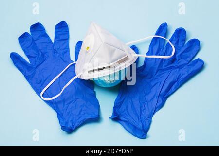 Medizinische Maske mit Ventil, Handschuhen und Spielzeugkugel auf dem Tisch. Das Konzept, persönliche Schutzausrüstung auf der ganzen Welt zu tragen Stockfoto