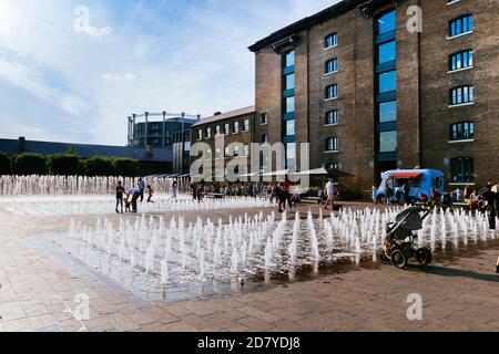 King's Cross London, Großbritannien, 12. Juli 2019: Kornspeicher-Platz Menschen genießen draußen, Brunnen Stockfoto