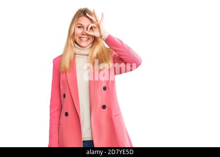 Junge schöne blonde Frau trägt elegante Kleidung tun ok Geste mit Hand lächelnd, Auge durch die Finger mit glücklichen Gesicht. Stockfoto