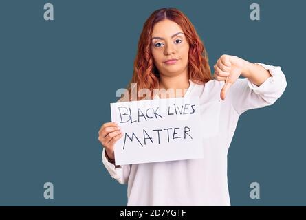 Junge lateinische Frau hält schwarze Leben Materie Banner mit wütenden Gesicht, negative Zeichen zeigt Abneigung mit Daumen nach unten, Ablehnung Konzept Stockfoto