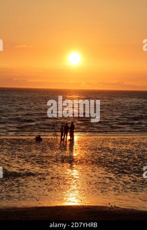 Prestwick, Ayrshire, Schottland, Großbritannien. Fischer genießen den Sonnenuntergang am Firth of Clyde mit Blick auf die Insel Arran. Ayr, Ayrshire, Schottland. Sept 2015 . Schattenmenschen mit Hund genießen einen abendlichen Spaziergang am Strand von Ayr entlang, während die Sonnenuntergänge über der Insel Arran. Platz für Text oder Text Stockfoto