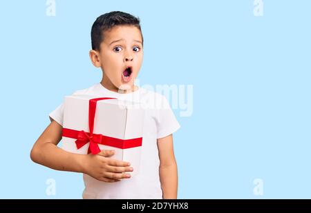 Kleine niedliche Junge Kind hält Geschenk verängstigt und erstaunt mit offenem Mund für Überraschung, Unglauben Gesicht Stockfoto