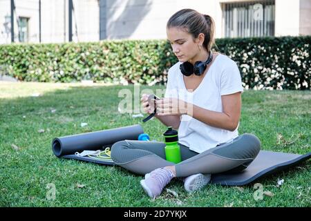 Junge kaukasische Frau, die ihre intelligente Uhr vor dem Training setzt. Outdoor-Übungskonzept. Stockfoto
