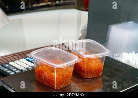 Roter Kaviar in transparenten Behältern stehen auf Schuppen auf dem Markt. Stockfoto