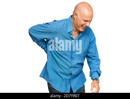 Kahlköpfiger Mann mittleren Alters in lässiger Kleidung mit Rückenschmerzen, Berührung mit der Hand, Muskelschmerzen Stockfoto