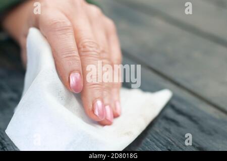 Nahaufnahme Handgelenk mit nassem Tuch oder Serviette abwischen ein Schwarzer Holztisch mit unscharfem Hintergrund Stockfoto