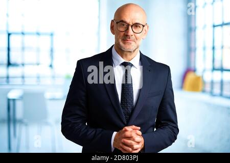 Porträt eines selbstbewussten Geschäftsmannes, der Anzug und Krawatte trägt, während er im Büro steht. Stockfoto