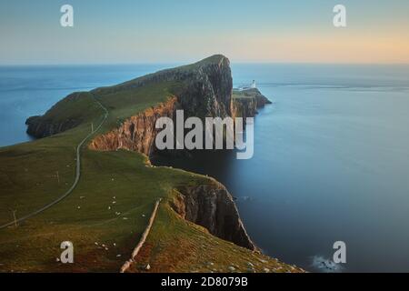 Eine Landschaft eines feinen Leuchtturms, der auf einer atemberaubenden Klippe vor dem Hintergrund des Meeres steht und von der untergehenden Sonne beleuchtet wird. Neist Point, Isle of Skye, Schottland Stockfoto