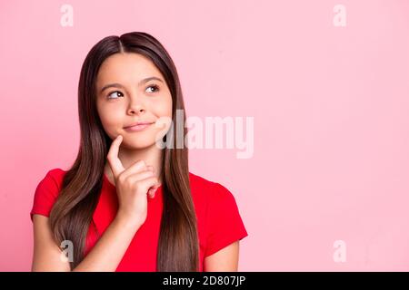 Foto von schönen niedlichen gesinnten nachdenklich kleine Dame lange Frisur Zeigefinger Gesicht Wangenknochen lächelnd verträumt tricky aussehen leeren Raum nachdenklich Tragen Sie rote T Stockfoto