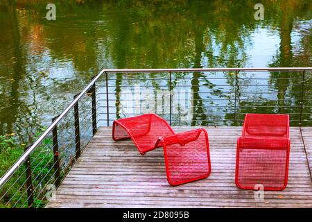 Rote Liegen am Hafen. Entspannen Sie sich in der herbstlichen Natur Stockfoto