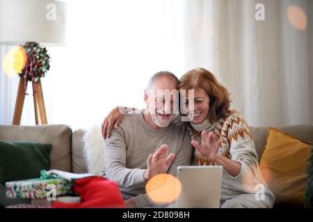 Seniorenpaar zuhause zu Weihnachten, mit Videoanruf mit der Familie. Stockfoto