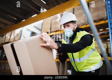 Mann Arbeiter arbeiten drinnen im Lager, coronavirus Konzept. Stockfoto