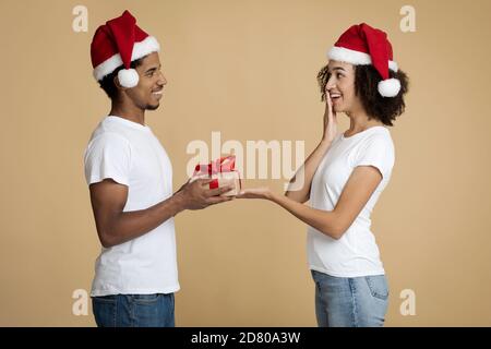 Junge gut aussehende bärtige afroamerikanische Mann gibt Frau Weihnachten Anwesend Stockfoto