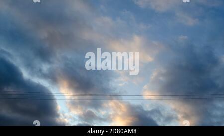 Stürmisches Wetter. Dunkle Wolke am Himmel. Sonnenlicht reflektiert auf den Wolken. Zwei Leitungslinien. Hintergrund für Text oder Design. Stockfoto