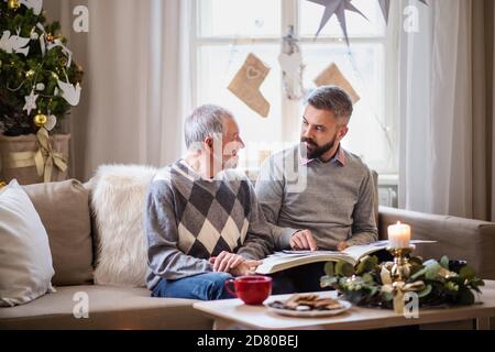 Reifer Mann und älterer Vater zuhause zu Weihnachten, Blick auf Phootgraphen. Stockfoto