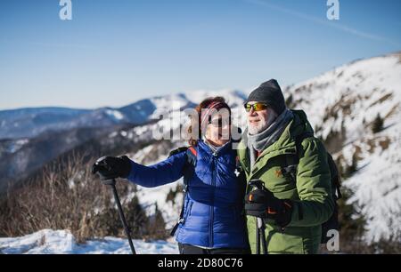 Ältere Wanderpaare mit nordic Walking Stöcken in schneebedeckter Winternatur. Stockfoto