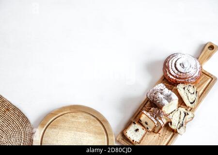 Verschiedene frische Backwaren werden auf einem Holzstab geschnitten. Auf einem hellen Hintergrund Platz für Text. Stockfoto