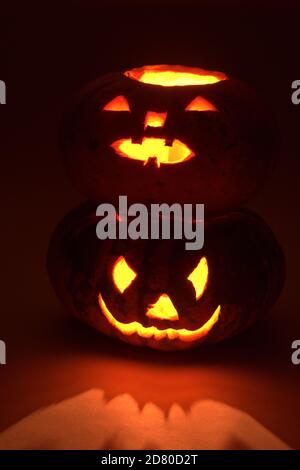 halloween Kürbis auf anderen halloween Kürbis. Geheimnisvolle rote Beleuchtung und Reflexionen. Geschnitzte gruselige Gesichter Stockfoto