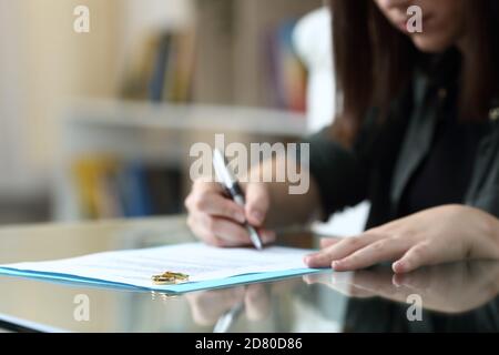 Frau Unterzeichnung Scheidung Dokument mit Eheringe über sie an Zu Hause Stockfoto