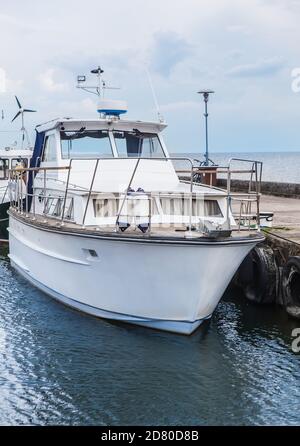 Weißes Motorboot, das am Pier an der Küste festgemacht ist. Stockfoto