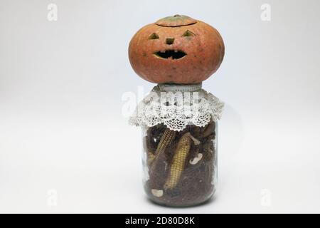 halloween Kürbis auf Flasche mit getrocknetem Mais. Symbolisch geschnitztes Gesicht auf leeren Kürbis ohne Laterne innen Stockfoto