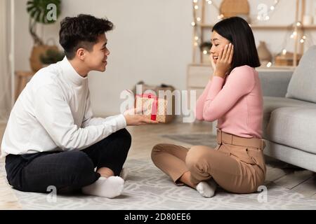 Chinesischer Ehemann Gibt Geschenk An Frau, Die Weihnachten Zu Hause Feiert Stockfoto