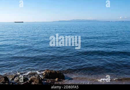 Drapetsona alter Hafen, Piräus, Griechenland. Silhouette von Frachtschiffen und Booten. Blick vom Strand auf festverankerte Schiffe im Hintergrund. Blauer Himmel und Meer eine sonnige da Stockfoto