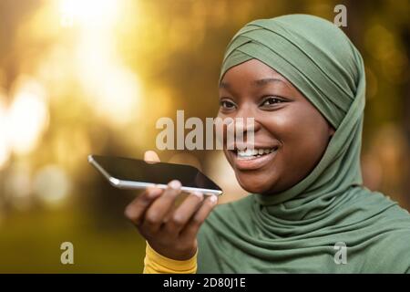 Happy Black Muslim Woman In Hijab Aufnahme Sprachnachricht Auf Smartphone Im Freien Stockfoto