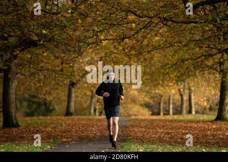 Liverpool, Großbritannien. Oktober 2020. Ein Läufer wird unter Herbstblättern im Sefton Park in Liverpool, Großbritannien, gesehen. Kredit: Jon Super/Alamy Live Nachrichten. Stockfoto