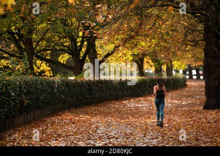 Liverpool, Großbritannien. Oktober 2020. Ein Läufer wird unter Herbstblättern in der Nähe von Sefton Park in Liverpool, Großbritannien, gesehen. Kredit: Jon Super/Alamy Live Nachrichten. Stockfoto